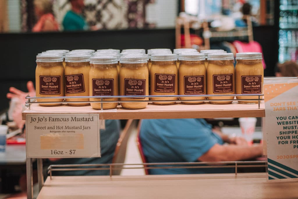 A shelf of Jo Jo’s Famous Mustard jars for sale, sweet and hot, sixteen ounces