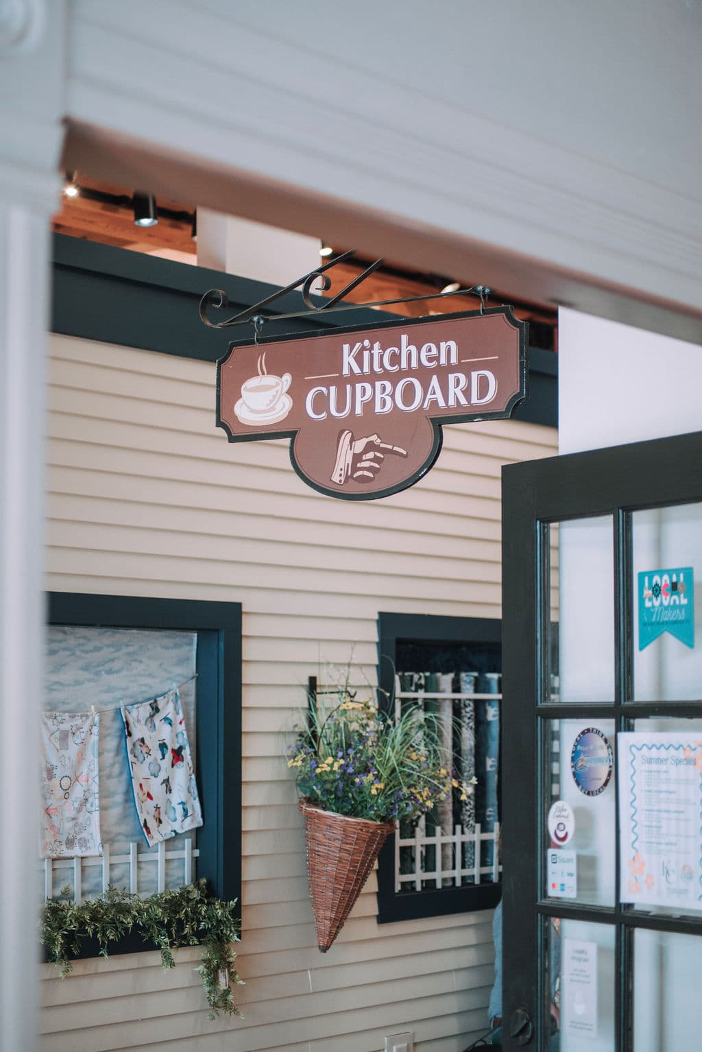 The hanging Kitchen Cupboard storefront sign with its pointing hand, above the shop entrance inside Davis Mercantile