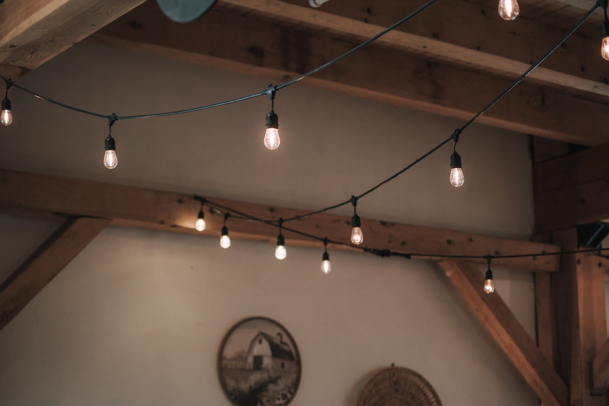 String lights hung along the timber beams, a barn plate on the wall below